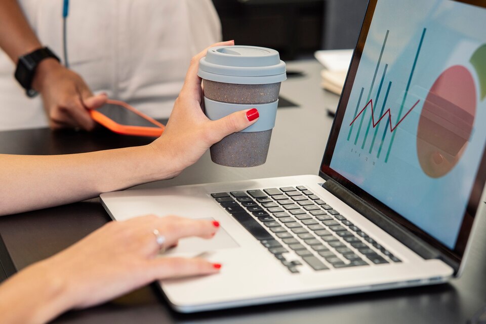 woman-s-hand-holding-coffee-while-using-computer-large